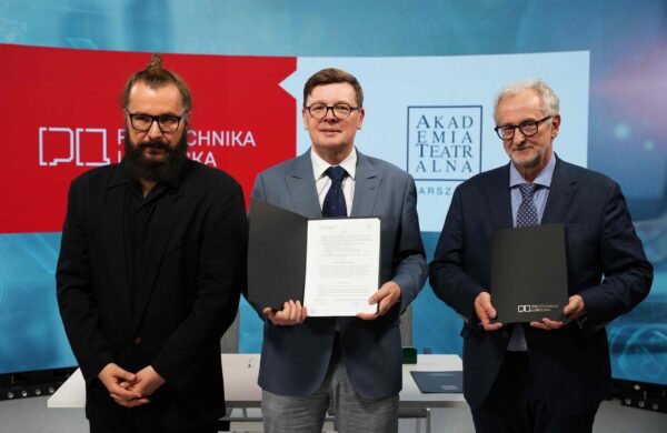 Trzej mężczyźni stoją obok siebie na tle oficjalnych logotypów uczelni. Mężczyzna w środku prezentuje otwartą czarną teczkę z podpisanym dokumentem, a mężczyzna po prawej trzyma zamkniętą teczkę z logo Politechniki Lubelskiej. Po lewej stoi trzeci mężczyzna w czarnej koszuli i marynarce.